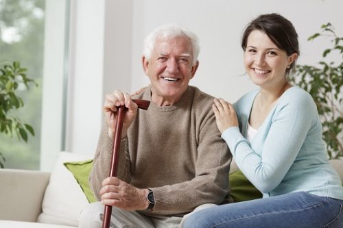 Smiling old man holding a cane and smiling young woman