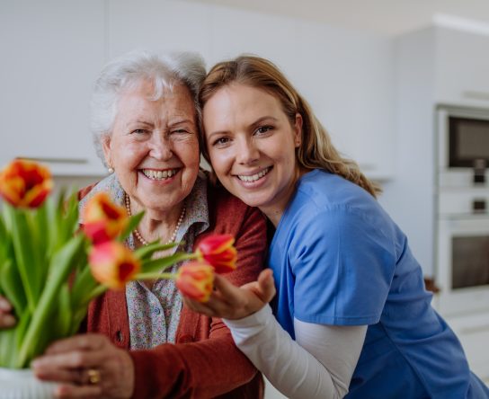 Senior woman and nurse with tulip bouquet.