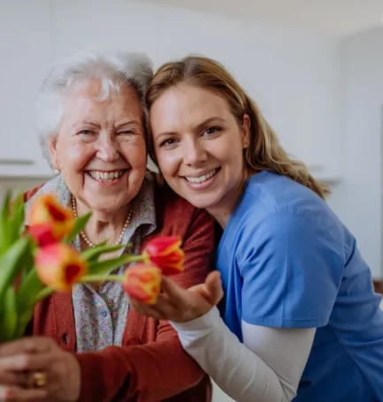 Senior woman and nurse with tulip bouquet.